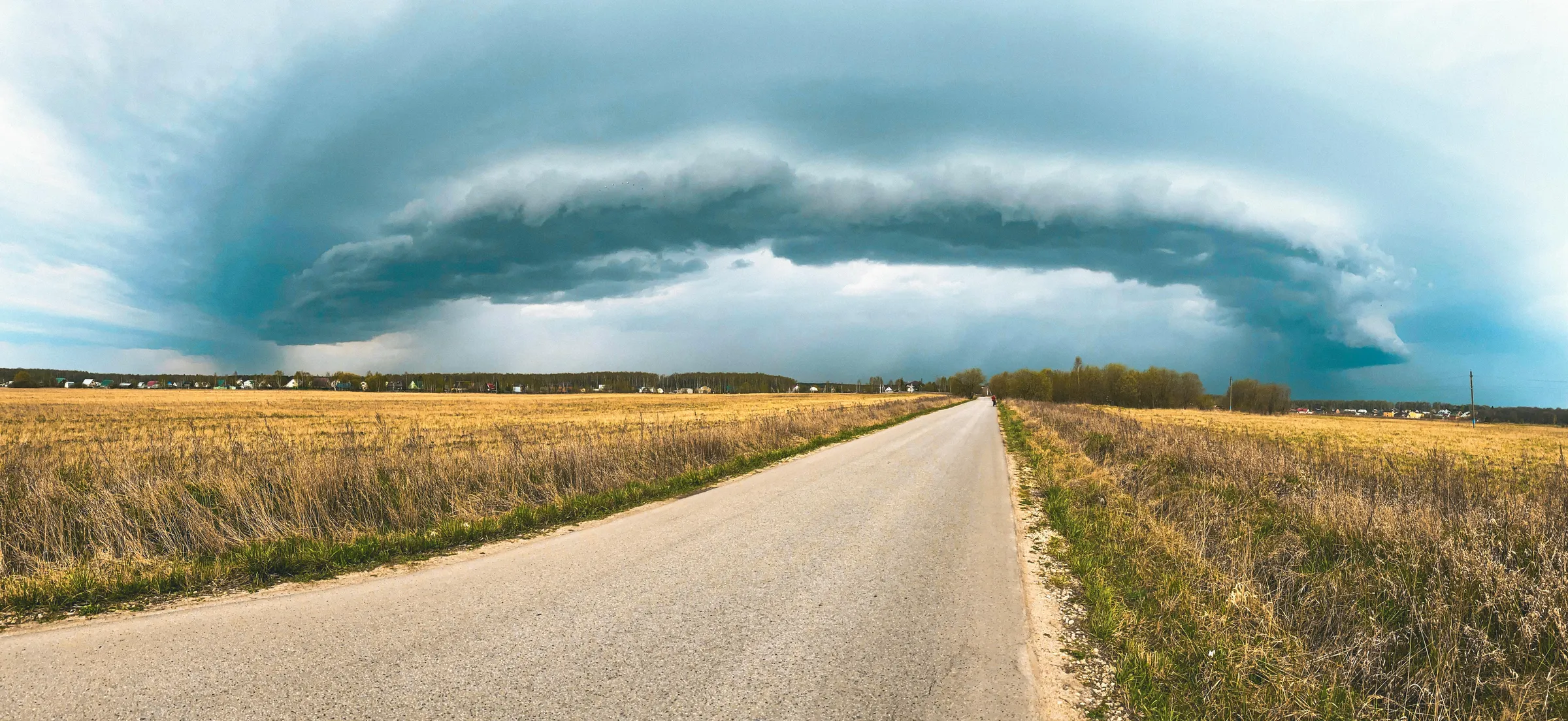 Arcus orageux au-dessus d'une route droite traversant un champ, l'orage que vous avancez vers